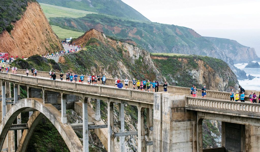 California Big Sur Marathon runners on bridge with ocean view