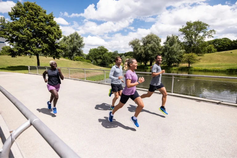 Group of men and woman running together along a paved path