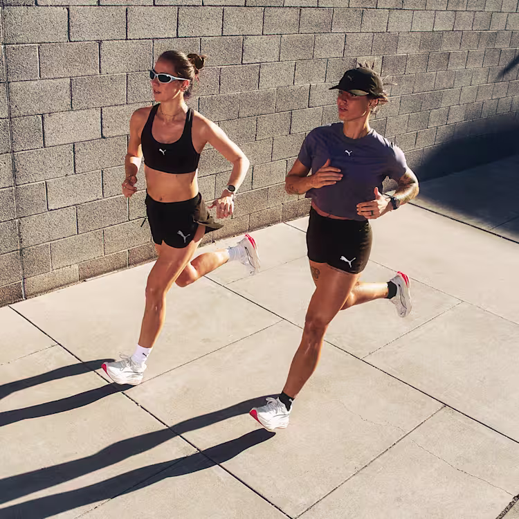 Two women running on the sidewalk in the Puma Deviate Pure Nitro wearing Puma attire