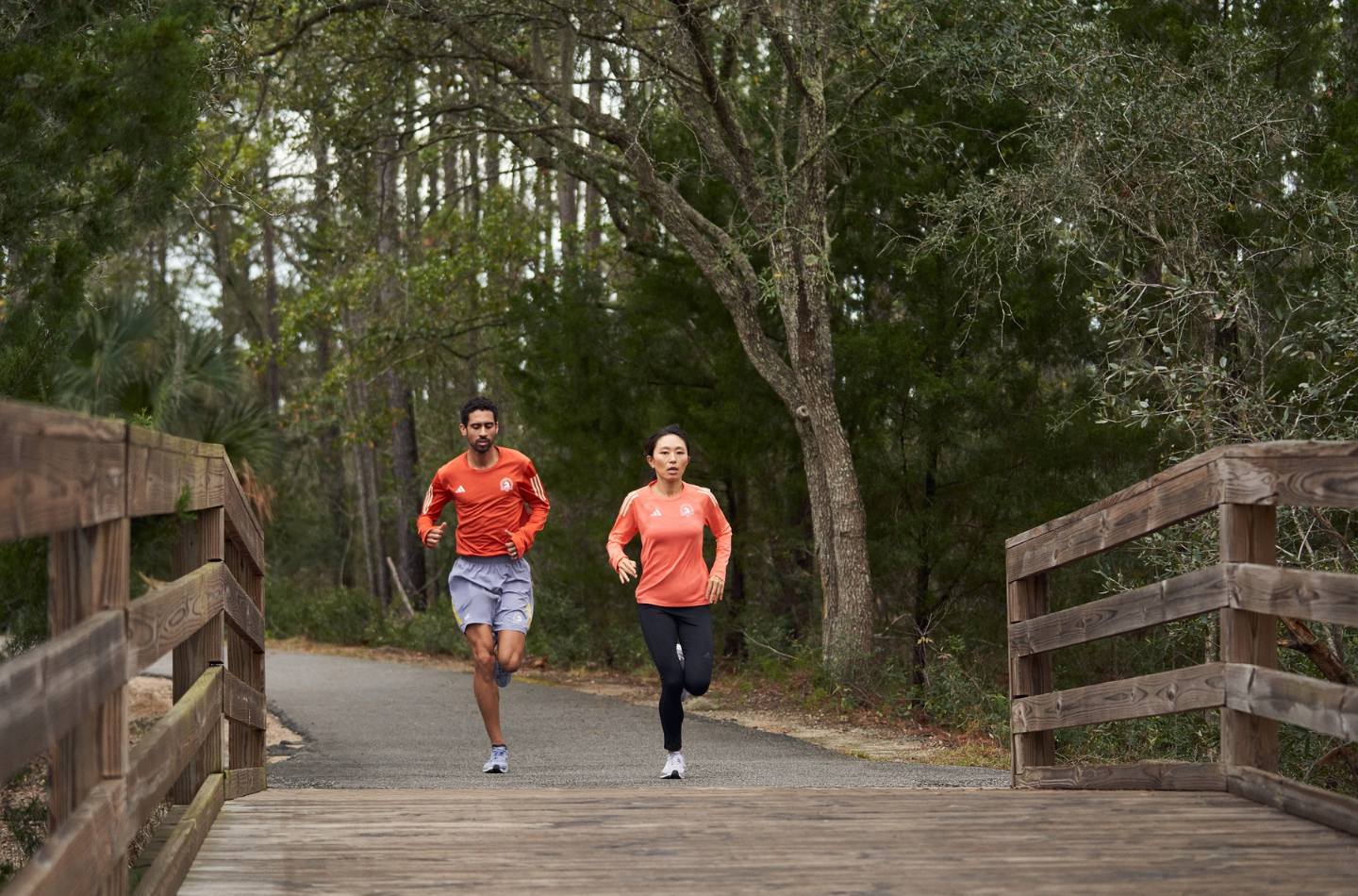 Man and woman running along a trail in Adidas running gear