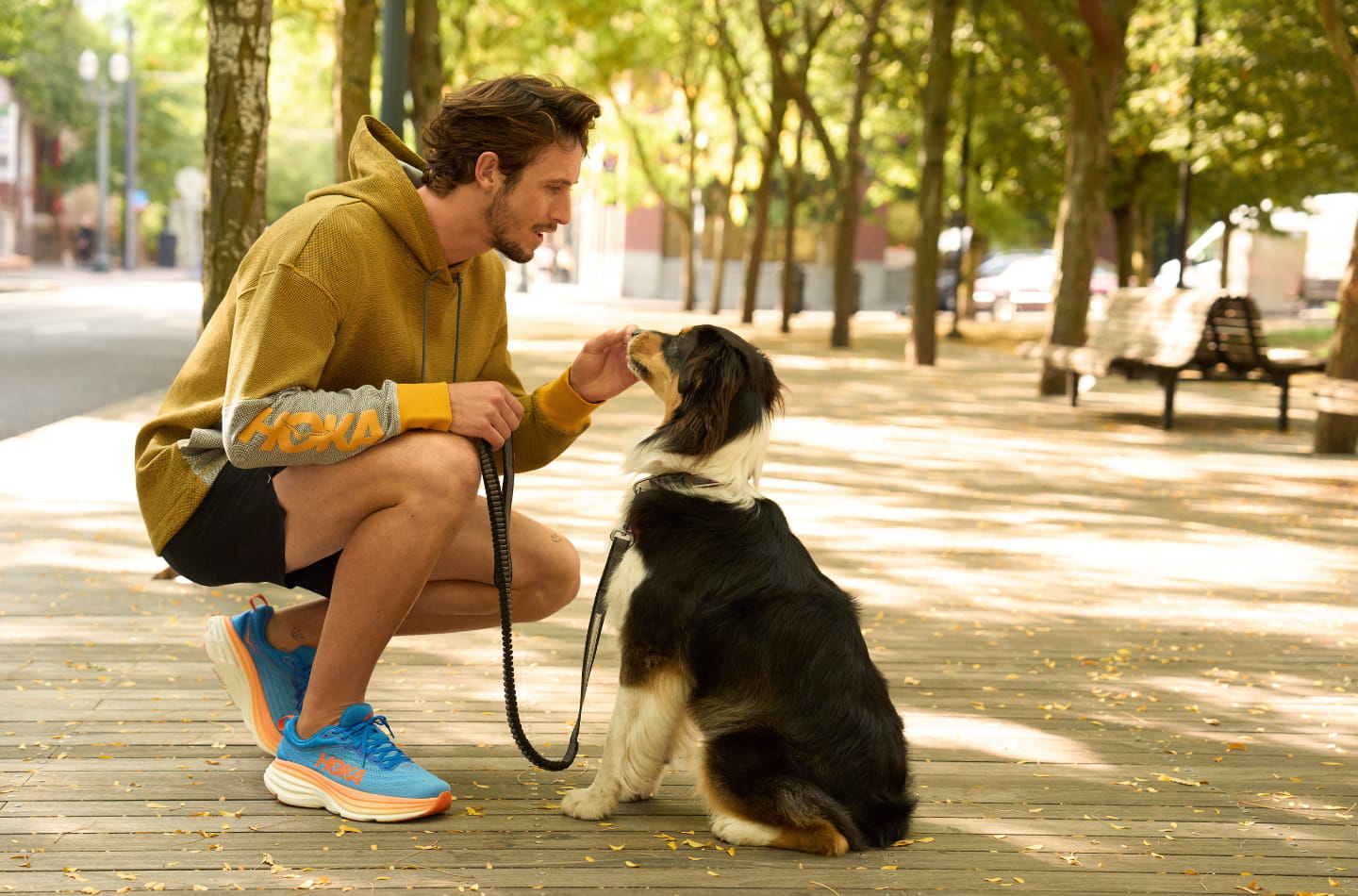 Man petting his dog while wearing the Hoka Bondi 8 Running Shoes